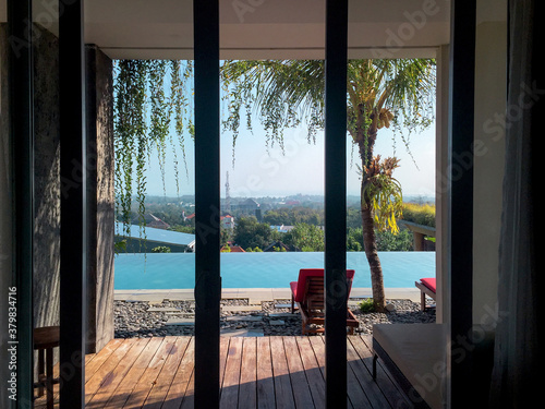 Windows views of a infinite pool and city from inside of a house photo