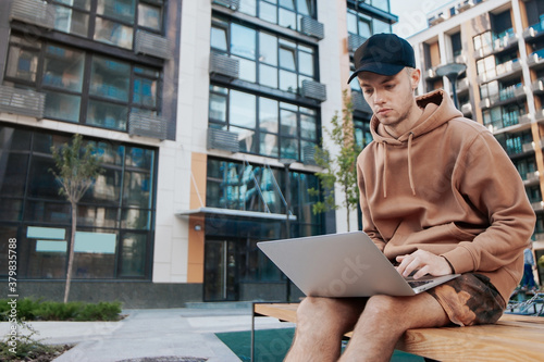 young blogger sitting with laptop on the street photo