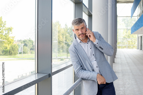 Businessman talking on mobile phone in front of an office