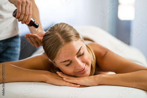 Professional masseur doing therapeutic massage. Woman enjoying massage in her home. Young woman getting relaxing body massage.