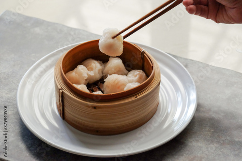Asian steamed dish. Dim sum on a food shelves, various Chinese steamed dumpling in bamboo basket steamer in Chinese restaurants. with a chopstick