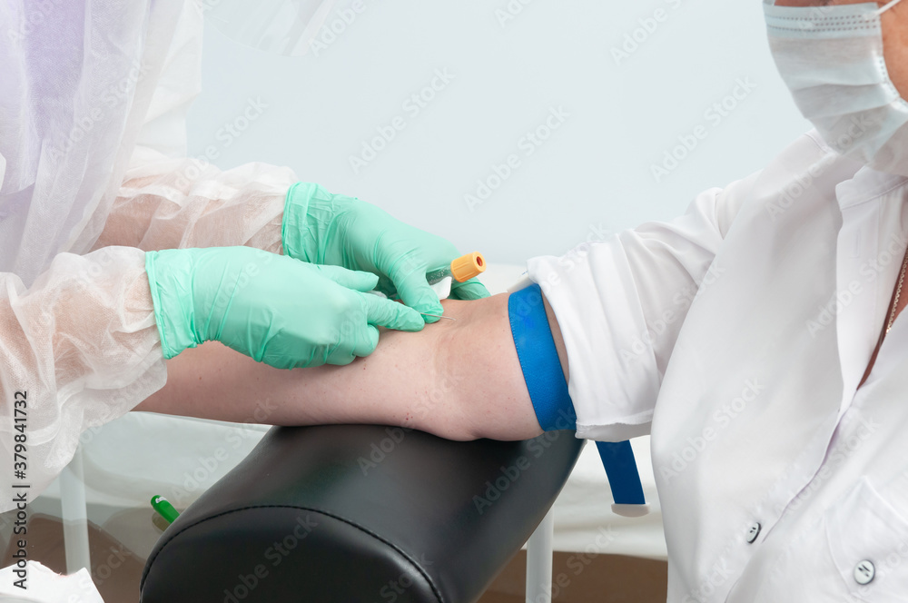 A nurse in a protective suit takes blood from a vein. Test for antibodies to Covid-19