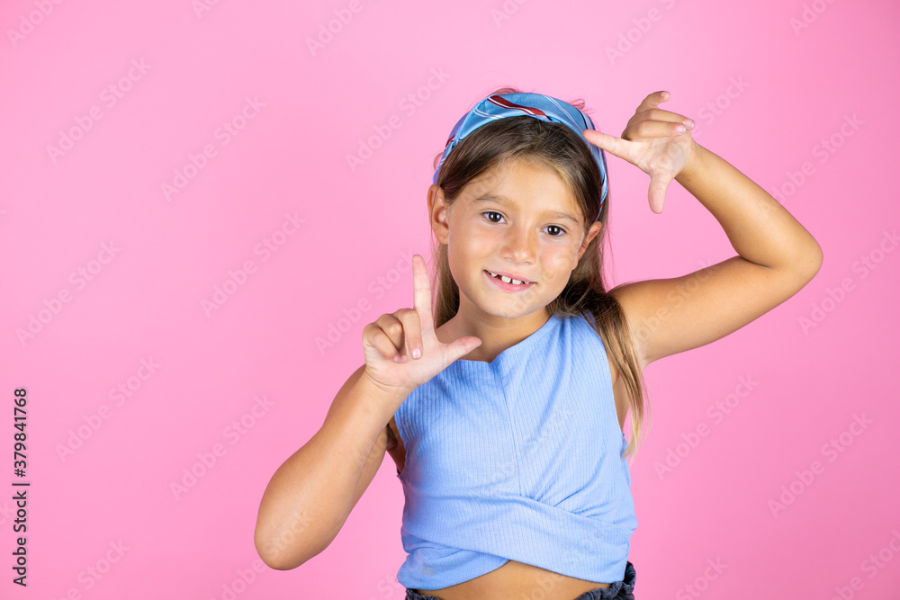 Young beautiful child girl over isolated pink background smiling making frame with hands and fingers with happy face Young beautiful child girl over isolated pink background smiling making frame with hands and fingers with happy face