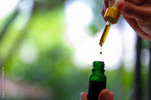 Drip hemp oil into a glass bottle.
Dropping an essential oil in the bottle. CBD oil. Cannabis. Scientific research. Medical education and research.