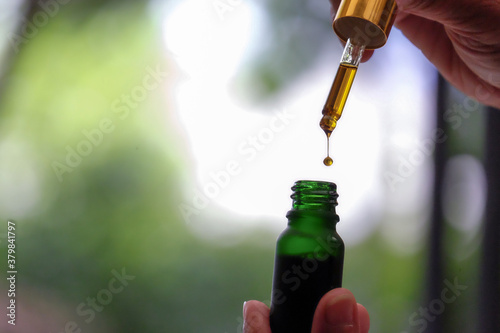Drip hemp oil into a glass bottle.
Dropping an essential oil in the bottle. CBD oil. Cannabis. Scientific research. Medical education and research.