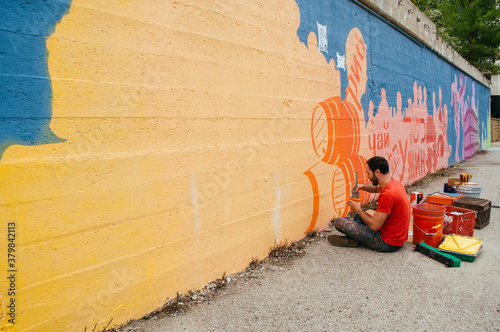 artist paints mural on a city street