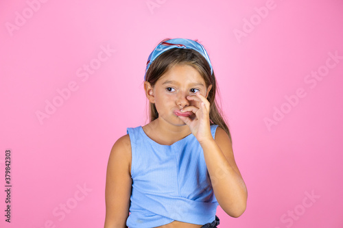 Young beautiful child girl over isolated pink background mouth and lips shut as zip with fingers. Secret and silent, taboo talking photo
