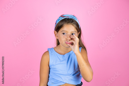 Young beautiful child girl over isolated pink background mouth and lips shut as zip with fingers. Secret and silent, taboo talking