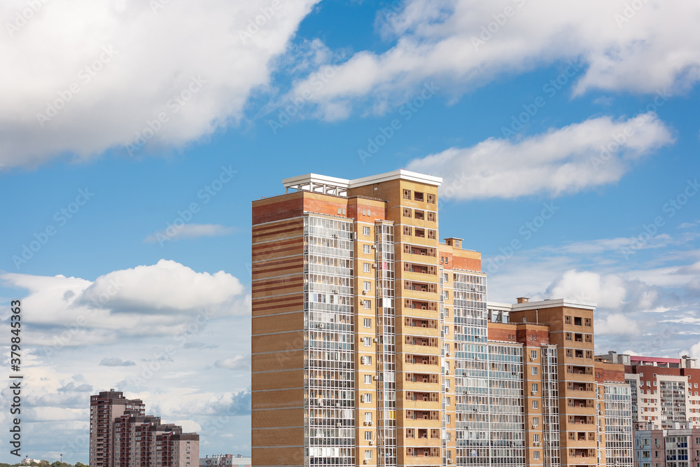 New block of modern apartments with balconies and blue sky with white fluffy clouds in the background New block of modern apartments with balconies and blue sky with white fluffy clouds in the background