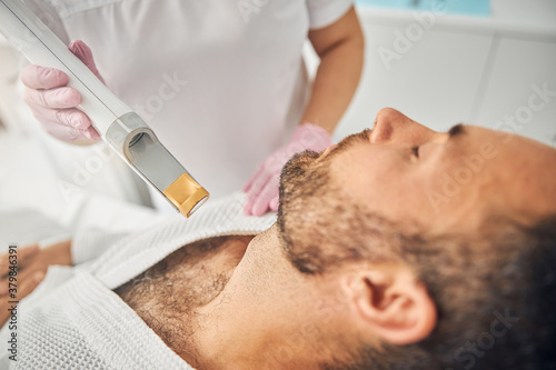 Bearded young man having laser hair removal procedure