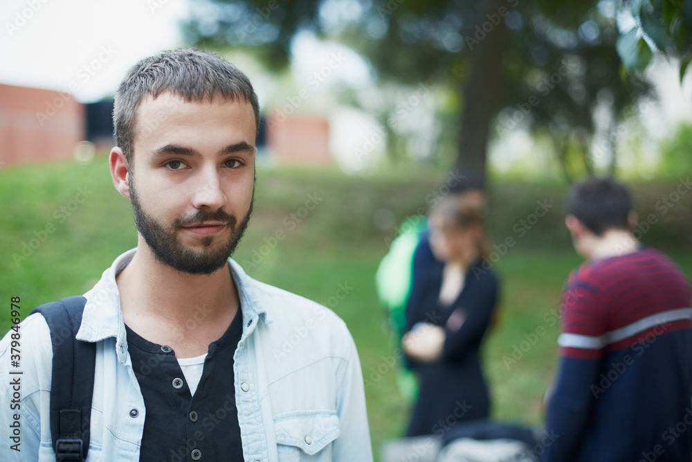 Young man with a group of students in the background looking at camera