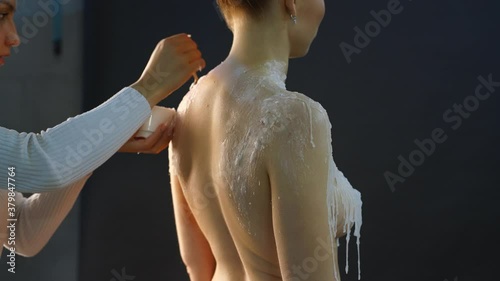 Crop artist applying wax on naked model