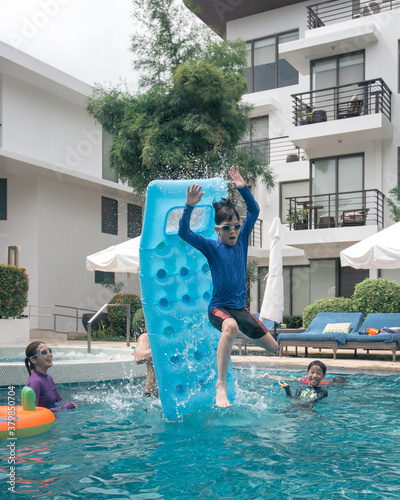 Young kid catapulted into the air using the inflatable in the swimming pool. photo