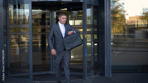 Businessman in a fromal suit in a business center enter the building with briefcase.