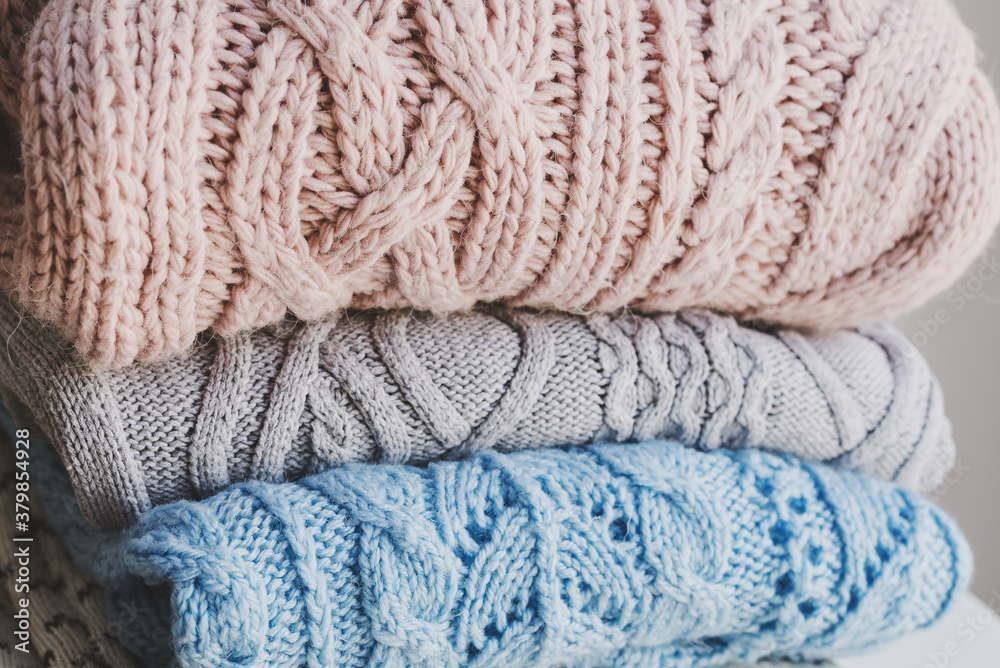 Pile of handmade knitted sweaters of pale pink, gray and blue color. Knitwear care concept. Warm clothing Pile of handmade knitted sweaters of pale pink, gray and blue color. Knitwear care concept. Warm clothing