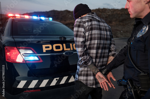 A Police Officer holds a suspect by handcuffs. photo