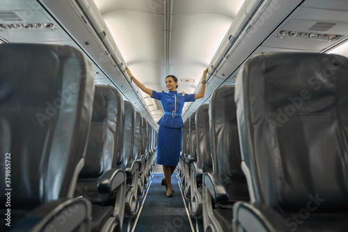 Contented professional flight hostess smiling in aircraft cabin