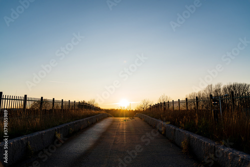 Paved road, with the sun rising behind the bridge first thing in the morning. © Xavi Lapuente