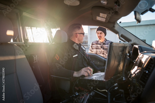 A Police Officer talks to a man at his vehicle window.