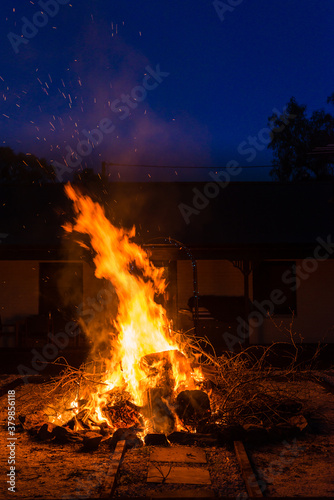 bonfire night, a large firepit roars with a large fire in an outdoor garden