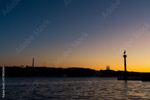 Crescent moon near the horizon. Behind the silhouette of the Stockholm skyline.