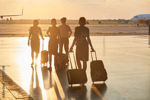 Slika na platnu Bright evening sunlight in the airport and crew members walking