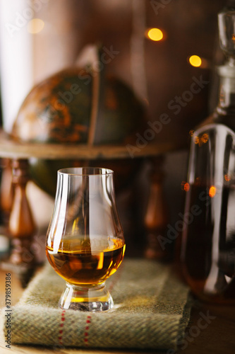 Whiskey glass with a pour of single malt whiskey and a decanter full of whiskey in the background. photo