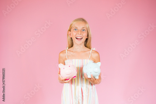 Girl showing two piggy bank she holds with a surprise expression © Danko