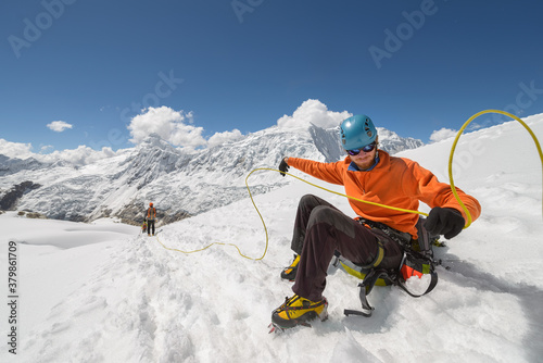 Mountain man giving rope to his fellow climbers photo