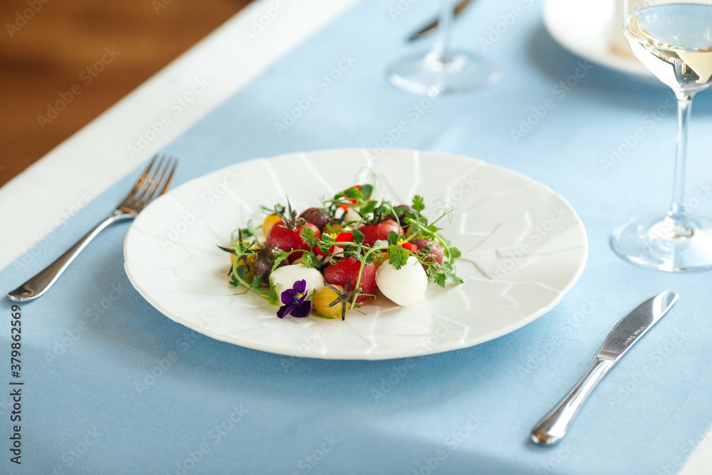Tomato salad with herbs on the blue served table Tomato salad with herbs on the blue served table