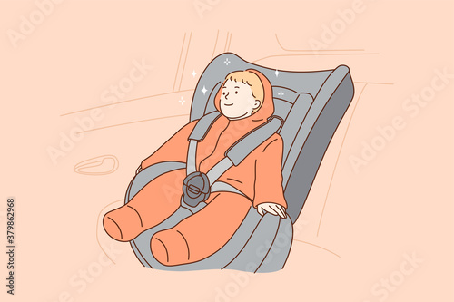 Transportation, safety, childhood concept. Young hapy smiling child kid boy infant toddler cartoon character sitting in special baby car seat in automobile. Children security in transport vehicle.