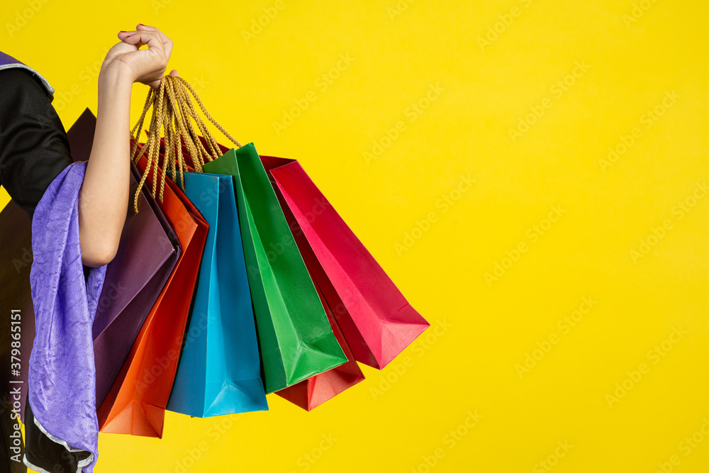 hand holding shopping bags on yellow background