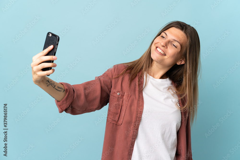 Young Slovak woman isolated on blue background making a selfie with mobile phone Young Slovak woman isolated on blue background making a selfie with mobile phone