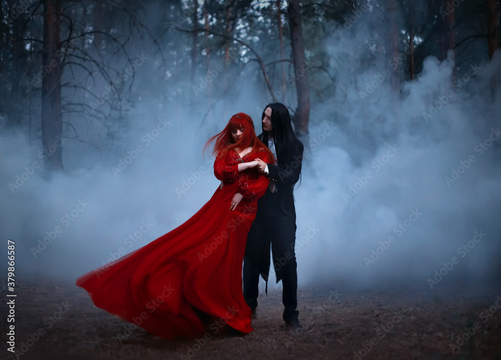 Blurred silhouette of a Gothic couple dancing in the fog. A vampire man in black tailcoat with long hair embraces seduces a woman in a long red medieval dress. The fabric and hair are flying in wind