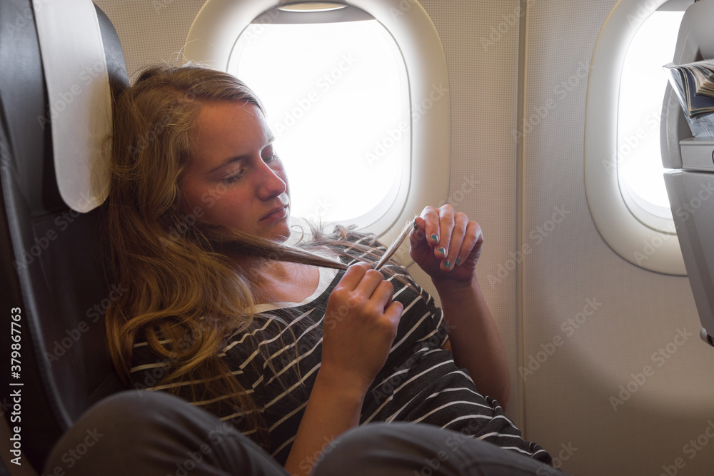 Young woman sitting beside the window on board of airplane Young woman sitting beside the window on board of airplane