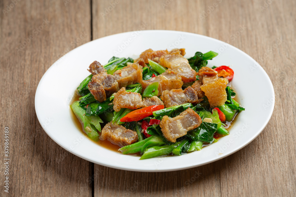 Stir fried kale, spicy crispy pork on wooden table Thai food concept. Stir fried kale, spicy crispy pork on wooden table Thai food concept.