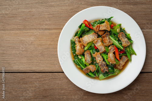 Stir fried kale, spicy crispy pork on wooden table Thai food concept.