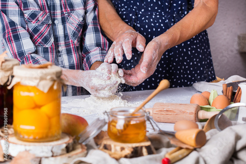 Grandmother with grandson cooking, kneading dough, baking in the kitchen