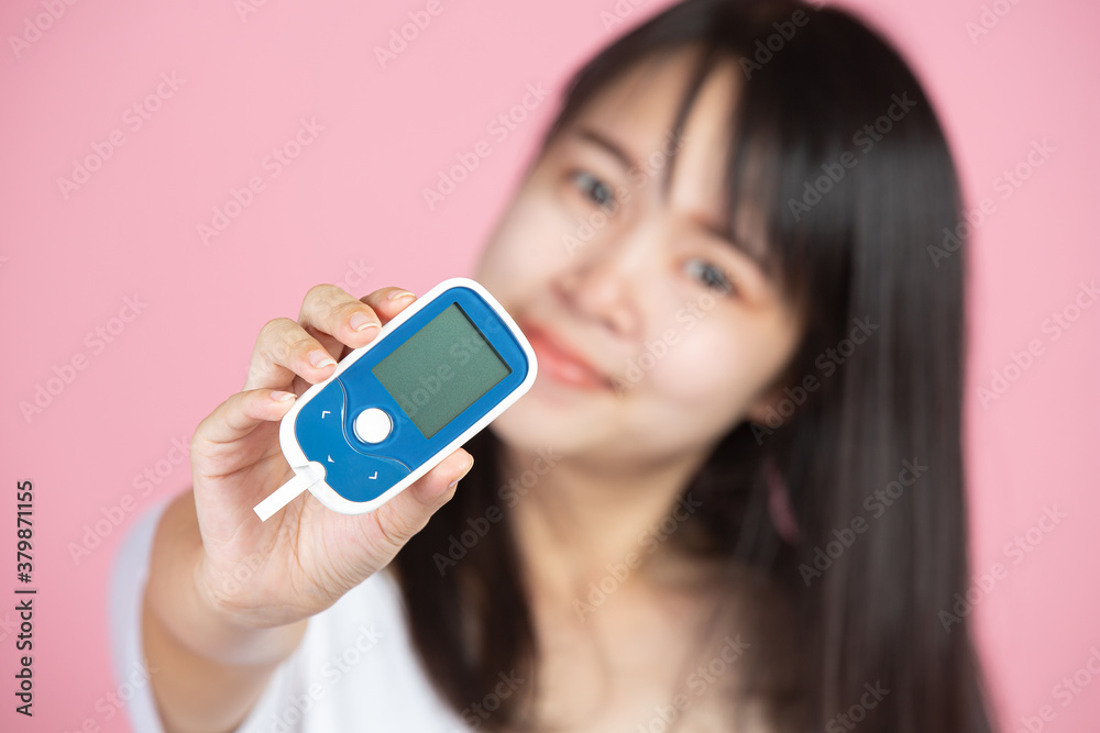 World diabetes day; woman holding Glucose meter on pink background World diabetes day; woman holding Glucose meter on pink background