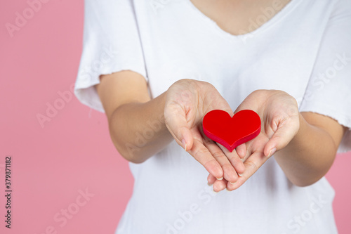 World diabetes day; hand holding red heart on pink background