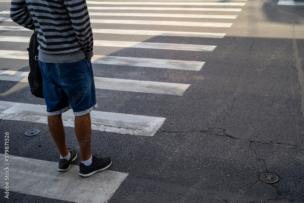 Man in short jeans and stripes blouse waiting at a pedestrian crossing. Man in short jeans and stripes blouse waiting at a pedestrian crossing.