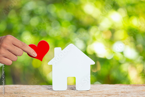 фотографія World Habitat Day,close up picture of a model house and hand holding paper heart