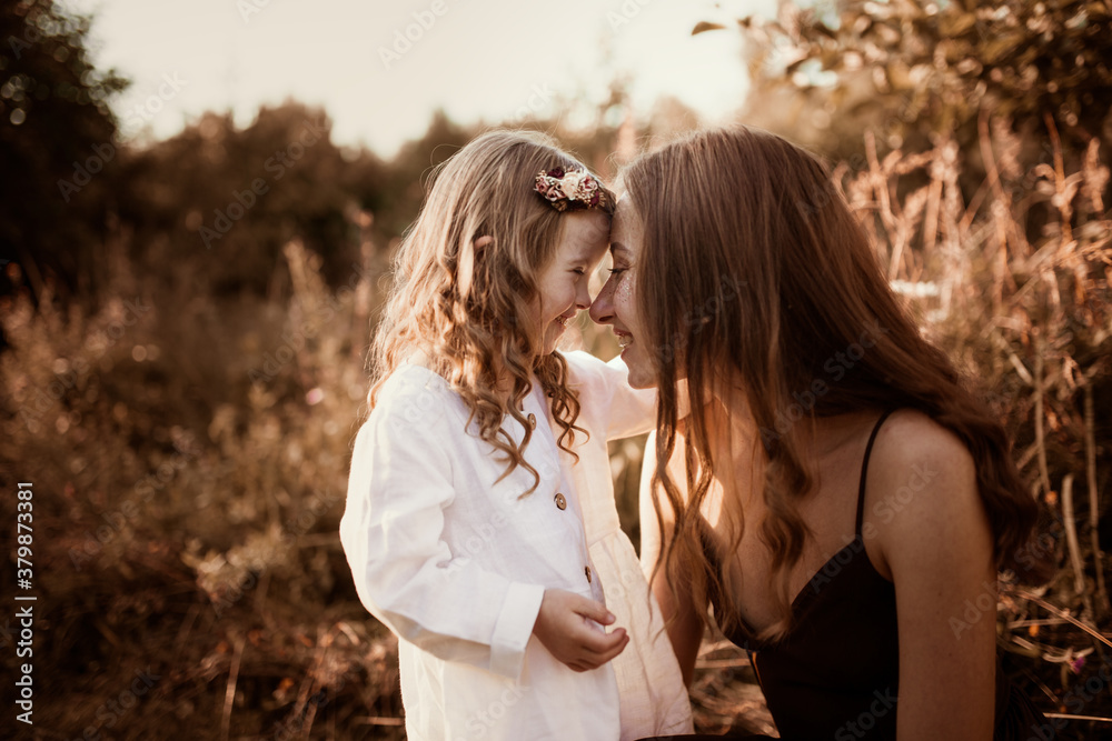Charming young Caucasian mom and daughter blonde with long hair in a field in summer, lifestyle and brown toning. Candid childhood and motherhood Charming young Caucasian mom and daughter blonde with long hair in a field in summer, lifestyle and brown toning. Candid childhood and motherhood