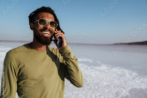 Image of happy african american man talking on mobile phone