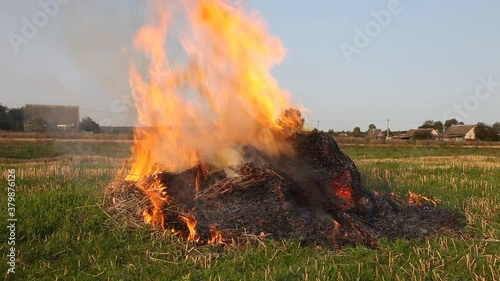 Bright burning haystack close up in the field with smoke, burning dry potato tops in the village on an autumn day, fire danger, ecology disaster pollutions