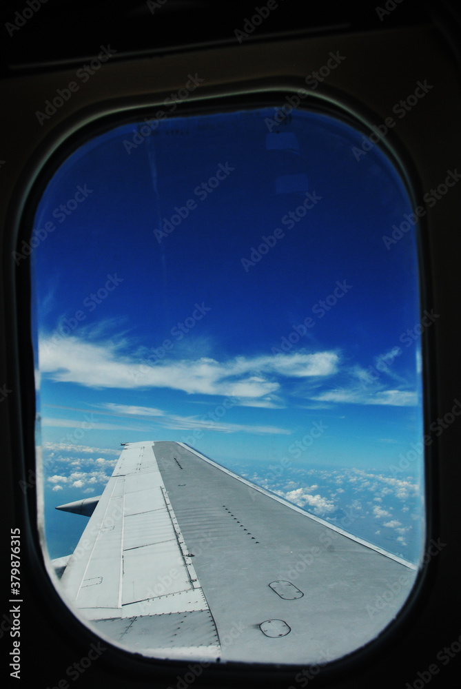 blue sky view from a window plane with wing in the foreground