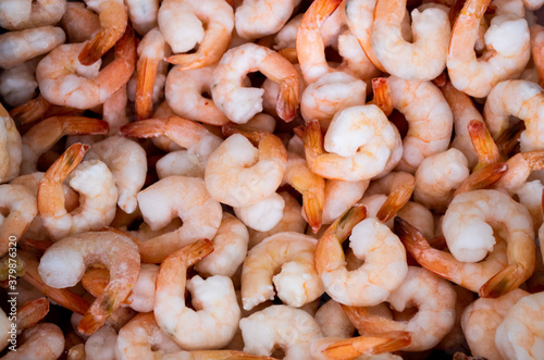 Close-up of a pile of frozen orange shrimps. Peeled shrimp, leaving only tails. Natural seafood background
