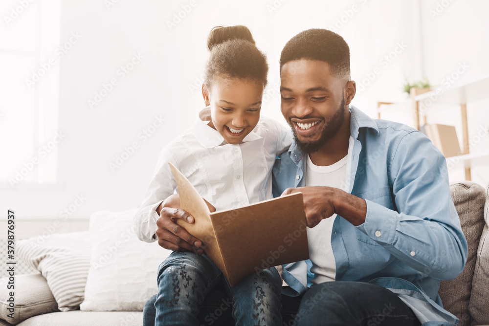 Happy evening. Afro dad reading fairy tale to his daughter - obrazy, fototapety, plakaty 