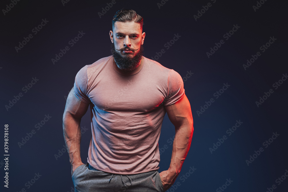 Fashionable and muscular with beard guy dressed in shirt and pants posing dark background. Fashionable and muscular with beard guy dressed in shirt and pants posing dark background.