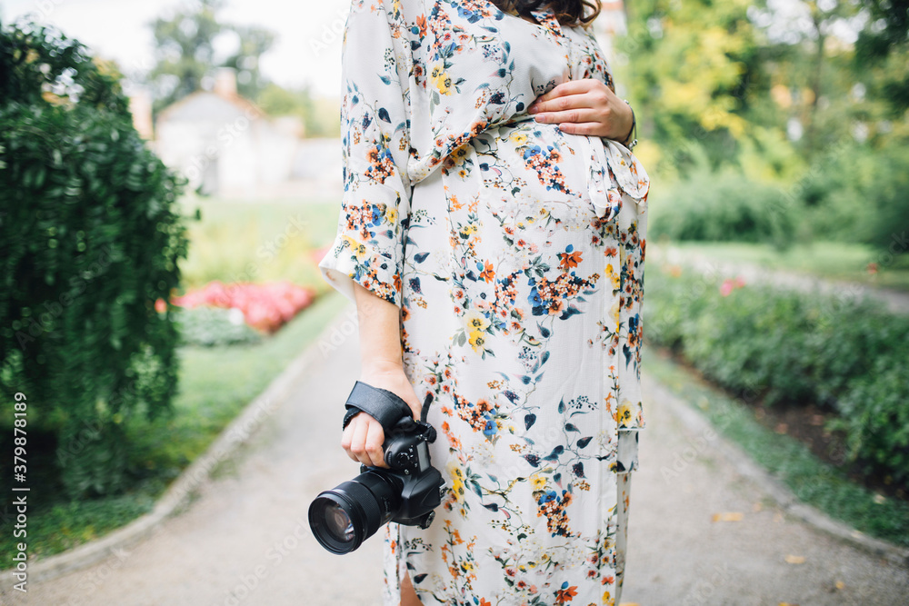 Beautiful pregnant woman in a floral dress walking Beautiful pregnant woman in a floral dress walking
